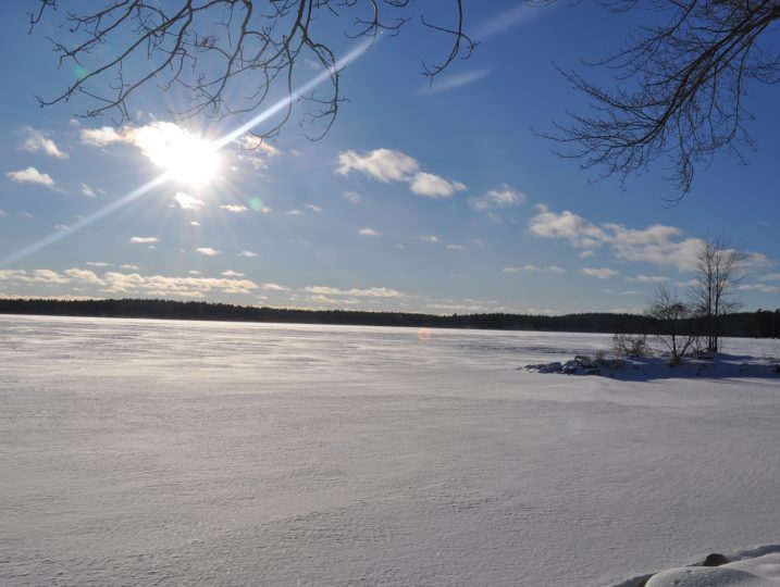 Wide winter view of frozen White Lake with blue sky and sunlight.